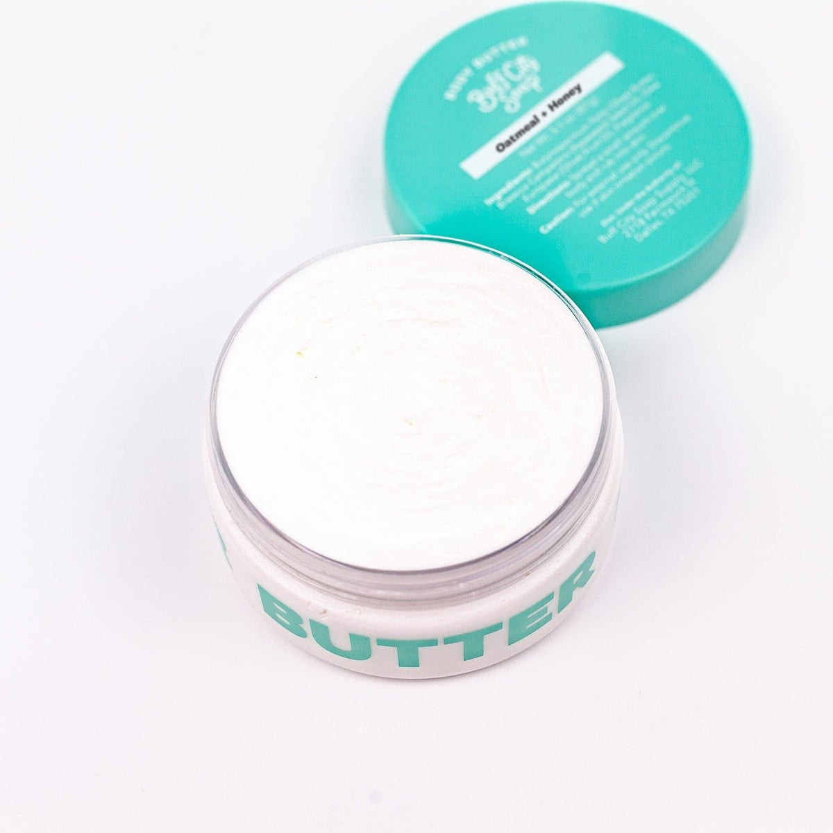 open container of Oatmeal + Honey Body Butter with lid placed next to it