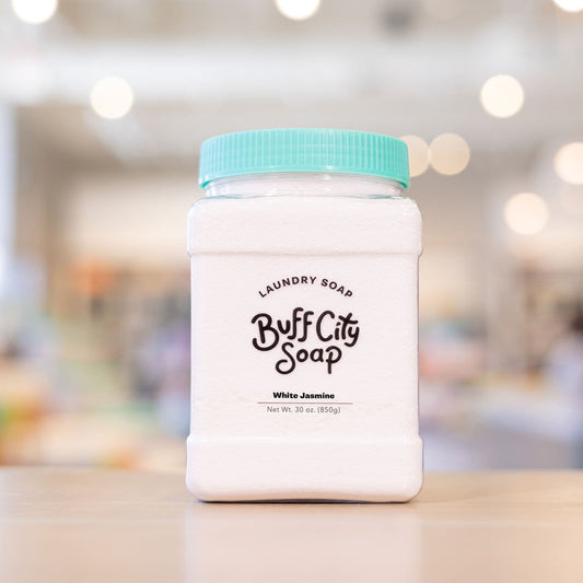 White Jasmine Laundry Soap with teal lid on wooden counter